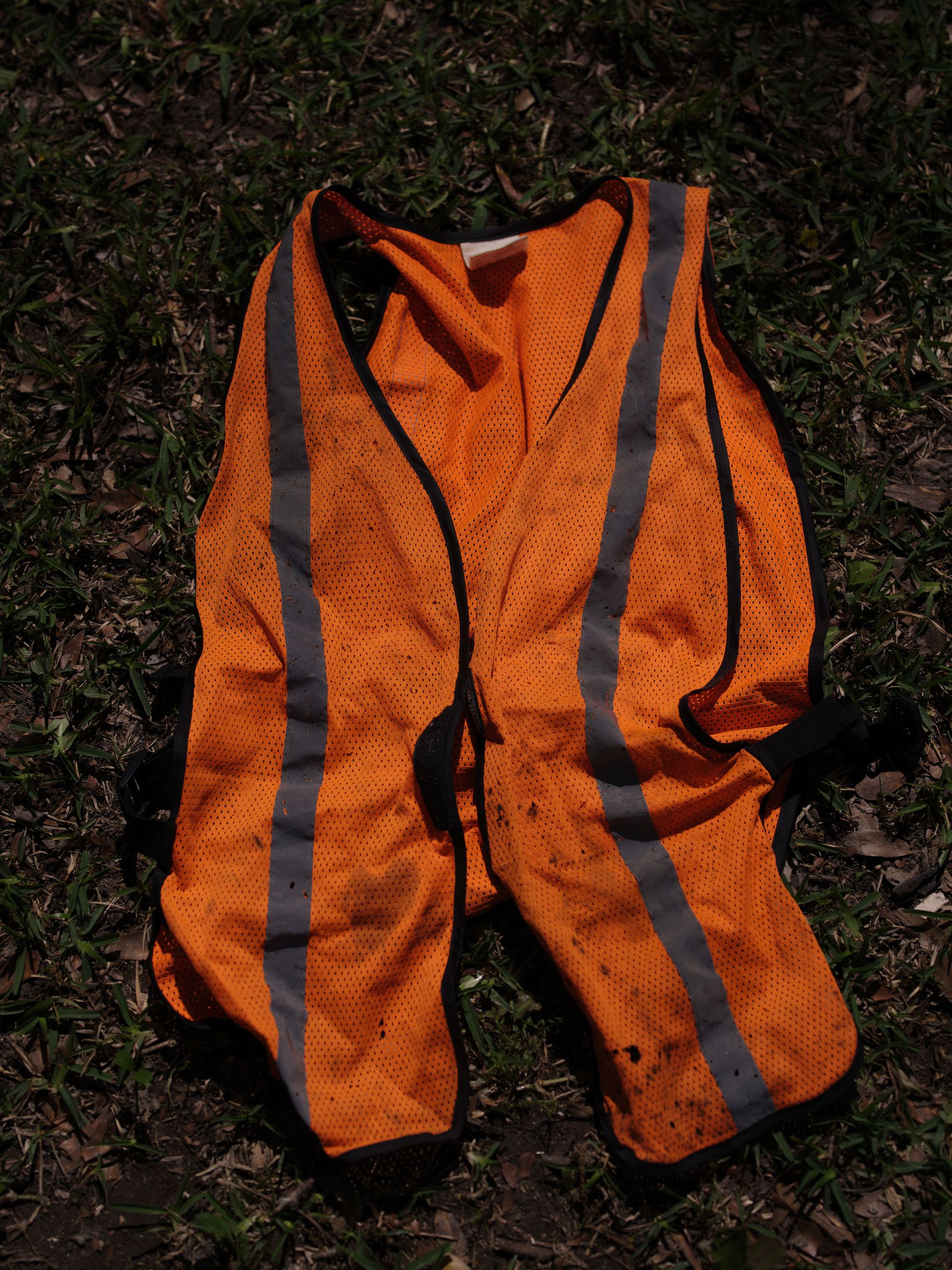 An overhead photo of an orange high-visibility work vest laid out on the ground.