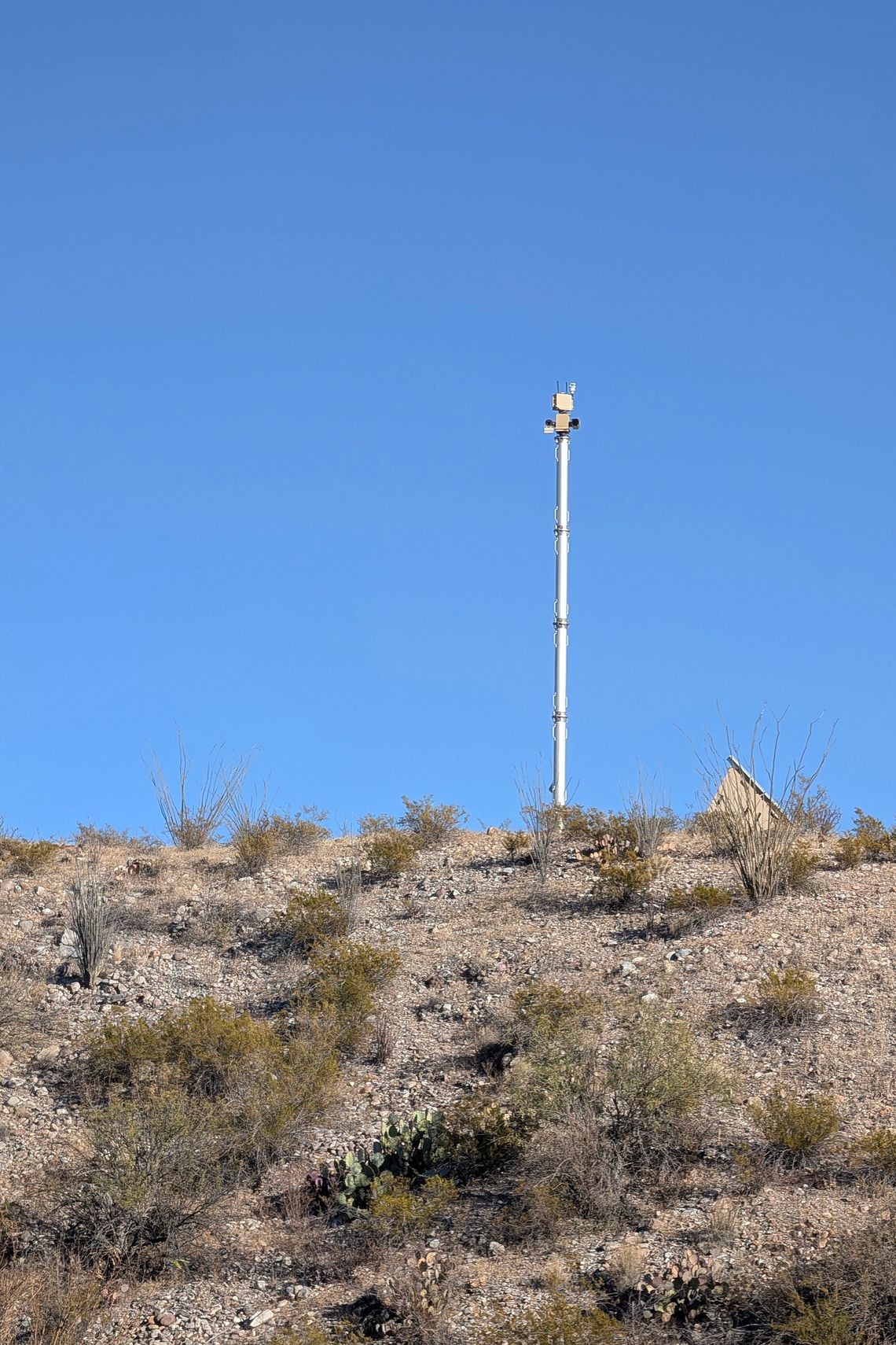 A photo shows a white surveillance tower at the top of a hill. 
