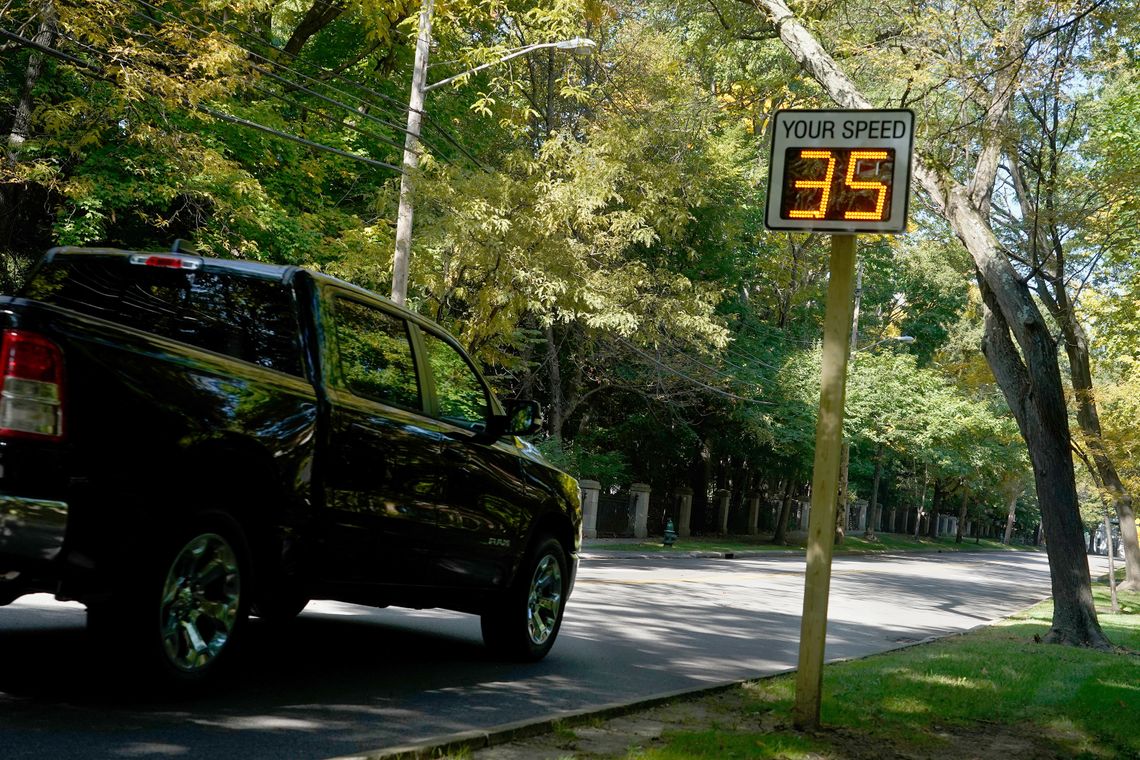 A black pickup trucks drives past a radar speed sign reading “35,” as it enters the 25-mph speed zone. 