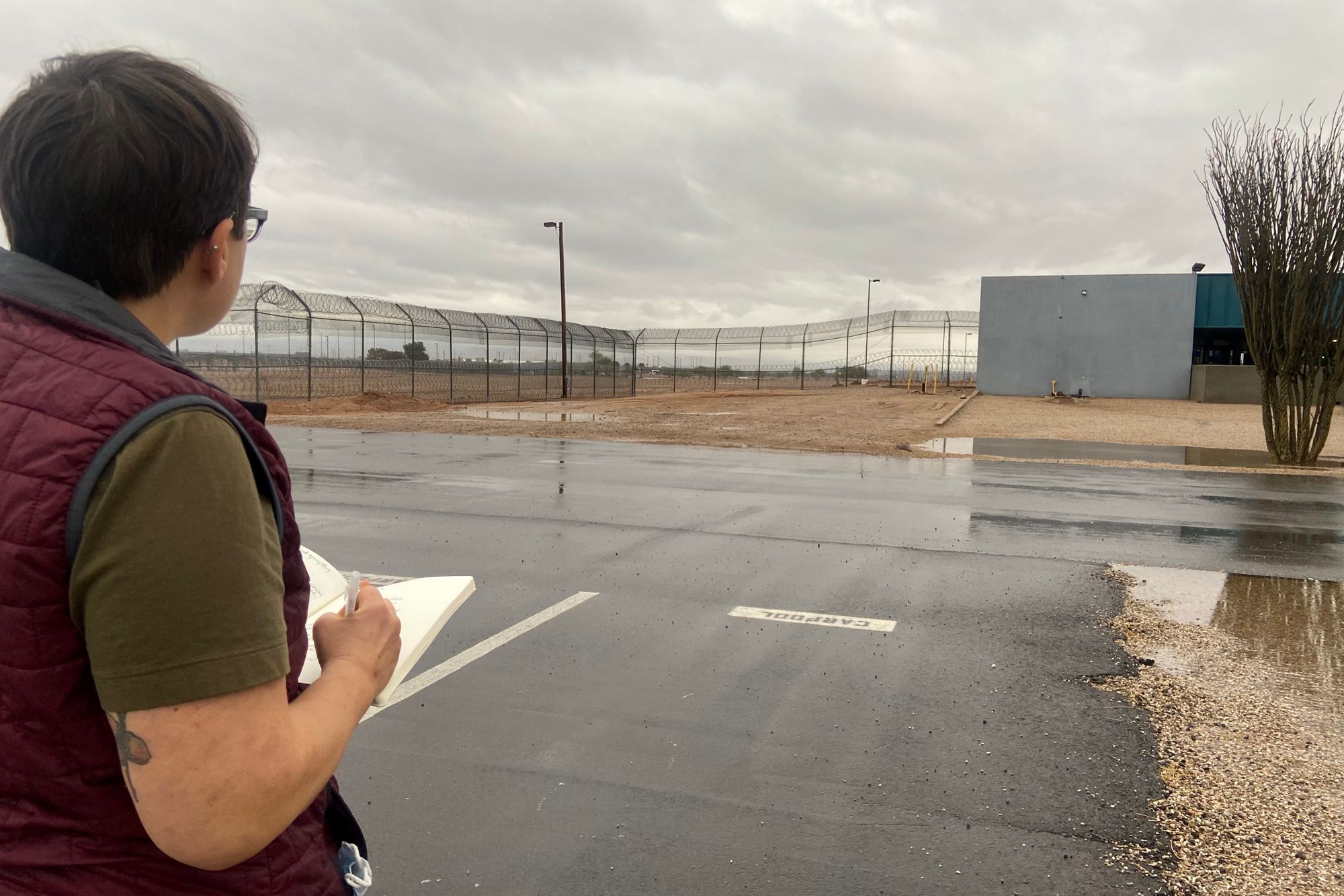 Beth Schwartzapfel, a White person, stands in the parking lot of a prison during the day. 