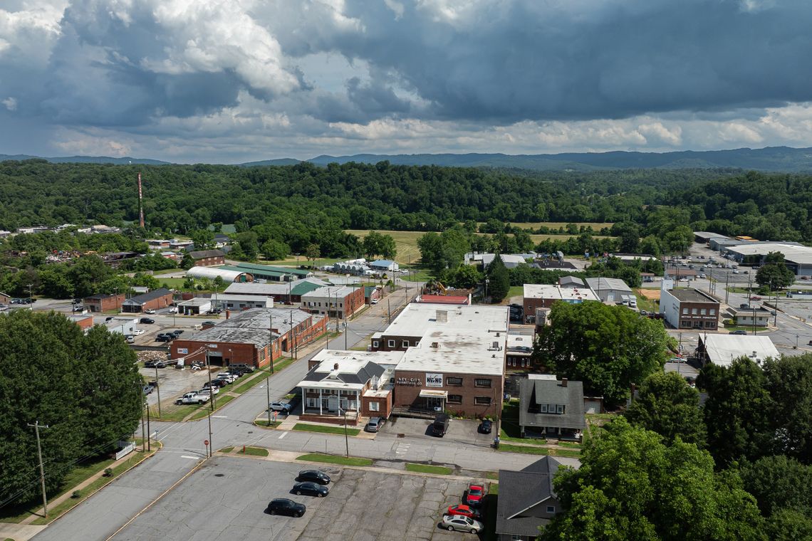 A photo shows an aerial view of a small downtown area with one- and two-story buildings. Green trees and low mountains are visible beyond the town. 