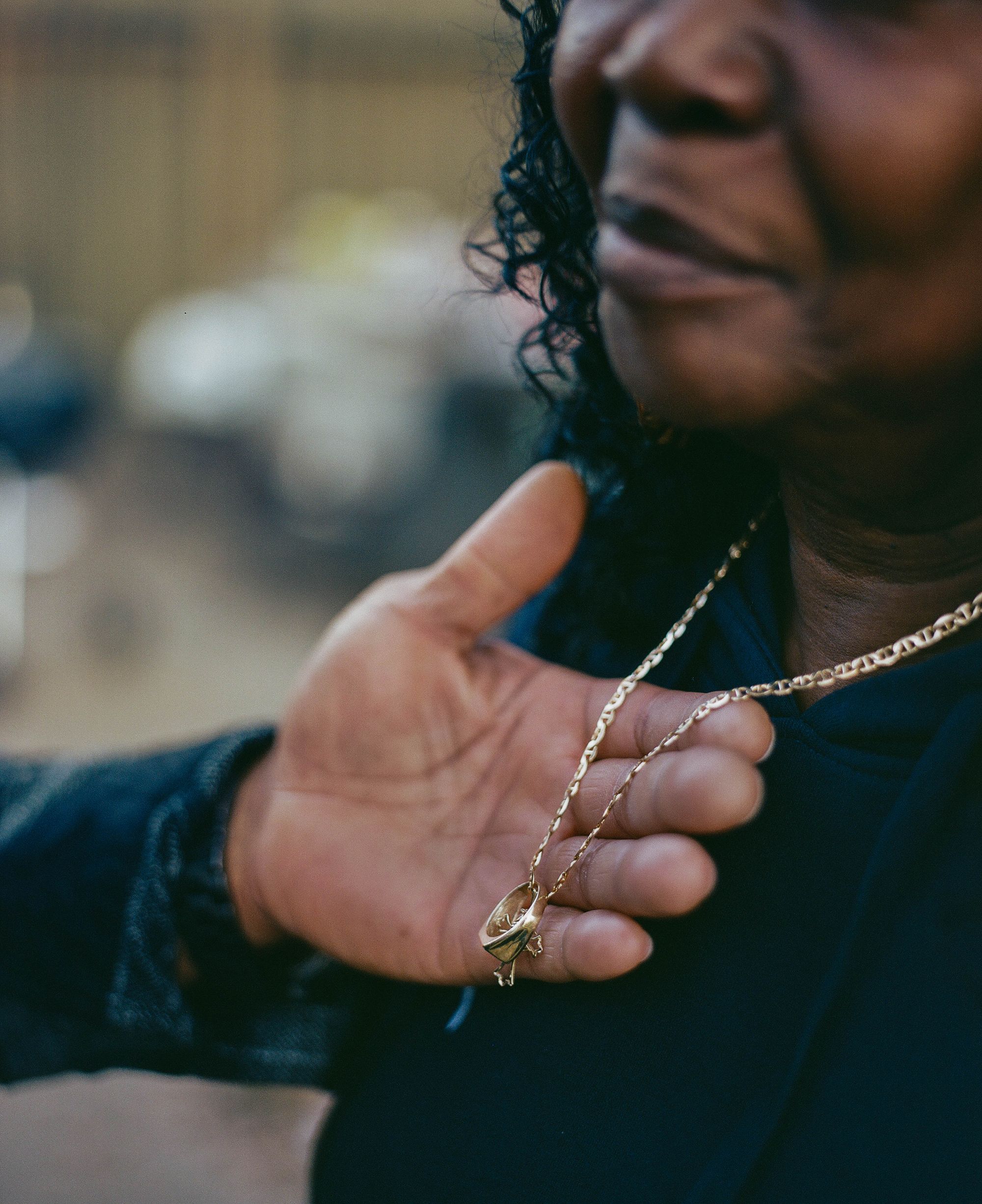 Moses lifts up a gold necklace hanging around Armour’s neck, which has a ring hanging from it. 