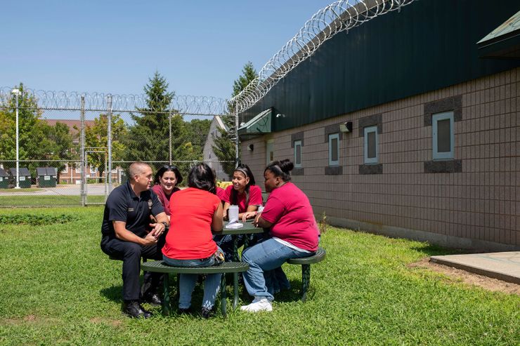 Lt. Russell Hanes, left, and counselor Colleen McClay, in bright red at center, chat with women who are incarcerated at York Correctional Institution in Niantic, Conn., in August.