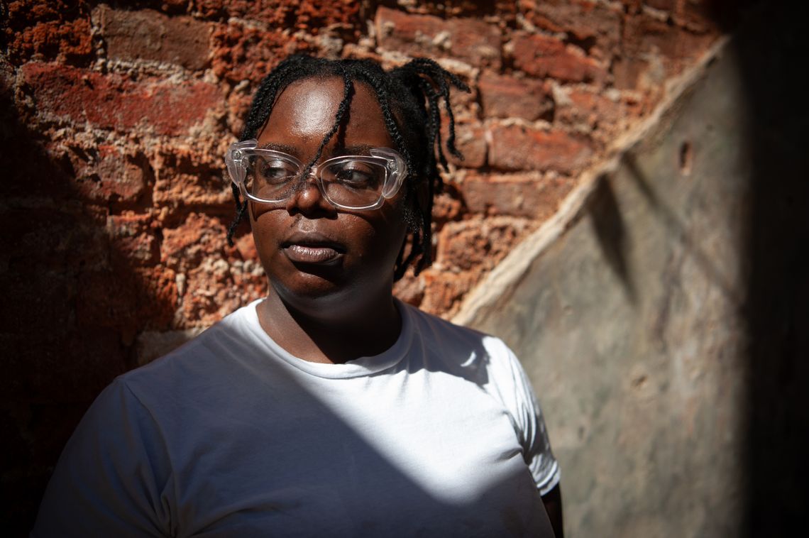 A Black woman with glasses looks off camera.