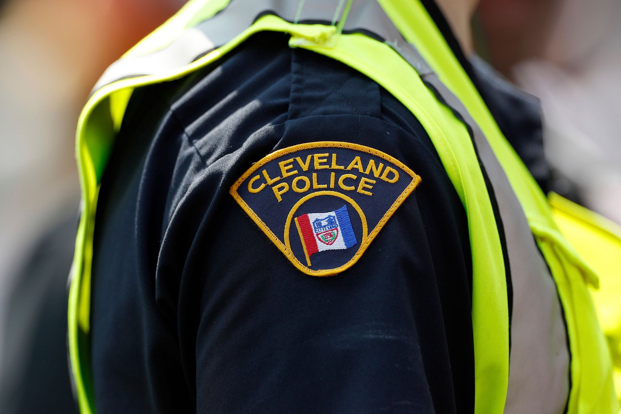 An officer in a neon green vest with a shoulder badge that reads "Cleveland Police." 