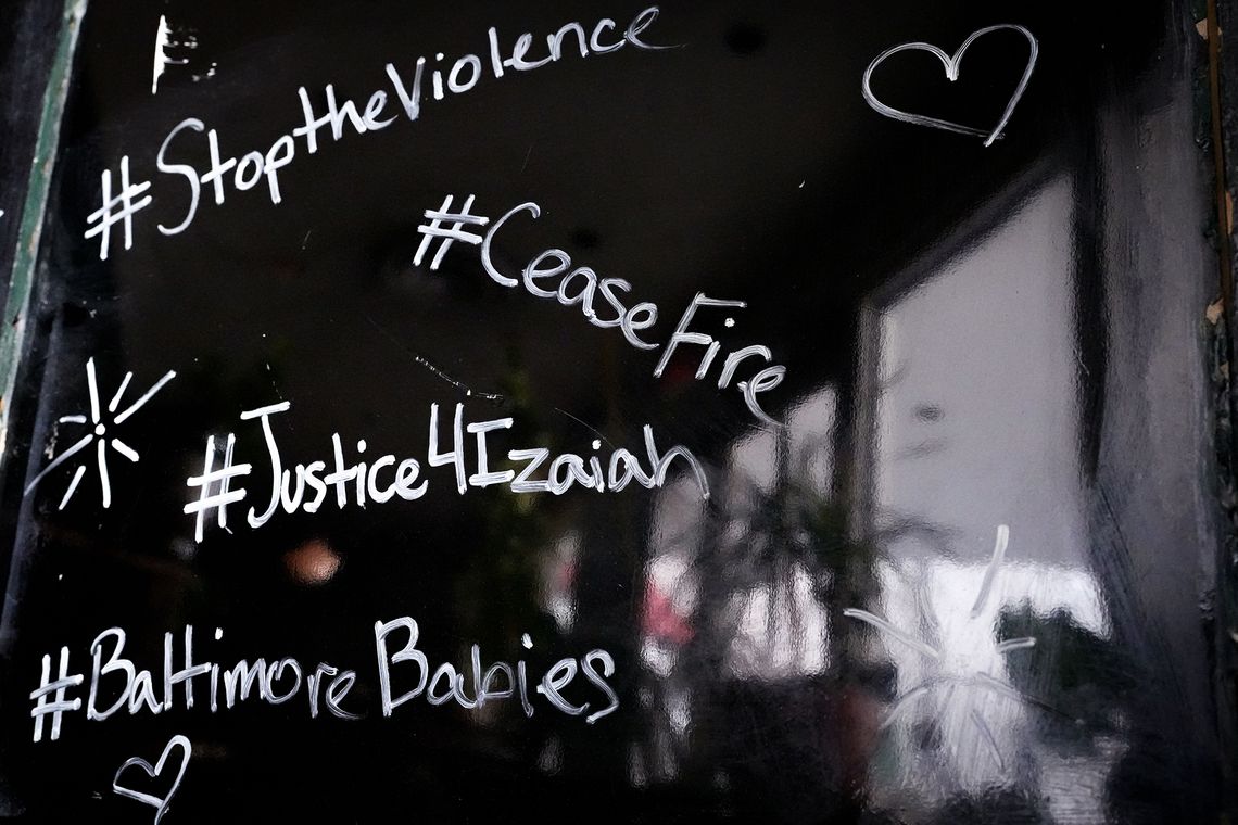 A black-colored sandwich board with messages such as “#StoptheViolence” and “BaltimoreBabies” written in white marker showing support for 16-year-old Izaiah Carter, who was shot and killed in March.