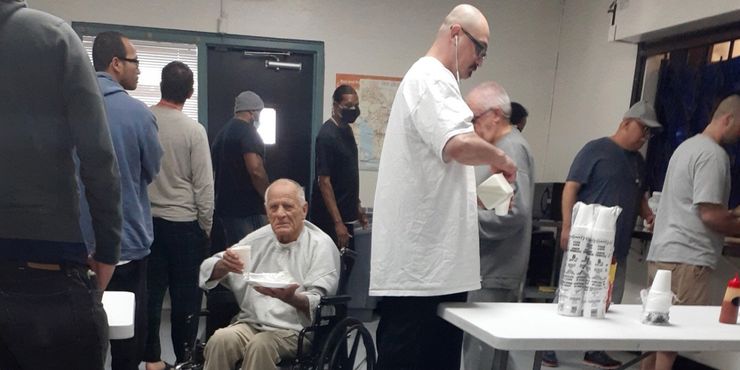 Few residents of Orion House wear masks as they line up for a meal at the federal halfway house in Van Nuys, California.