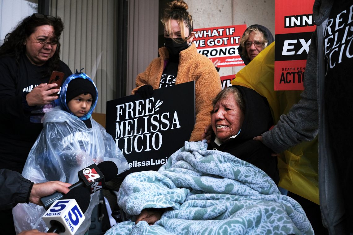 77-year-old Esperanza Treviño sits in front of the Cameron County Courthouse, with members of the press holding microphones in front of her, as family and friends stand nearby. 