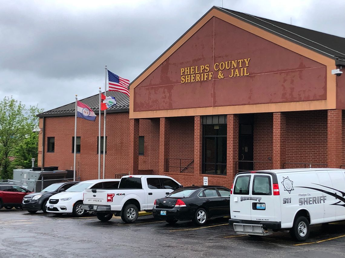 A photo of an orange brick building with a sign that reads “Phelps County Sheriff and Jail.” Several cars are parked in front of the building. 