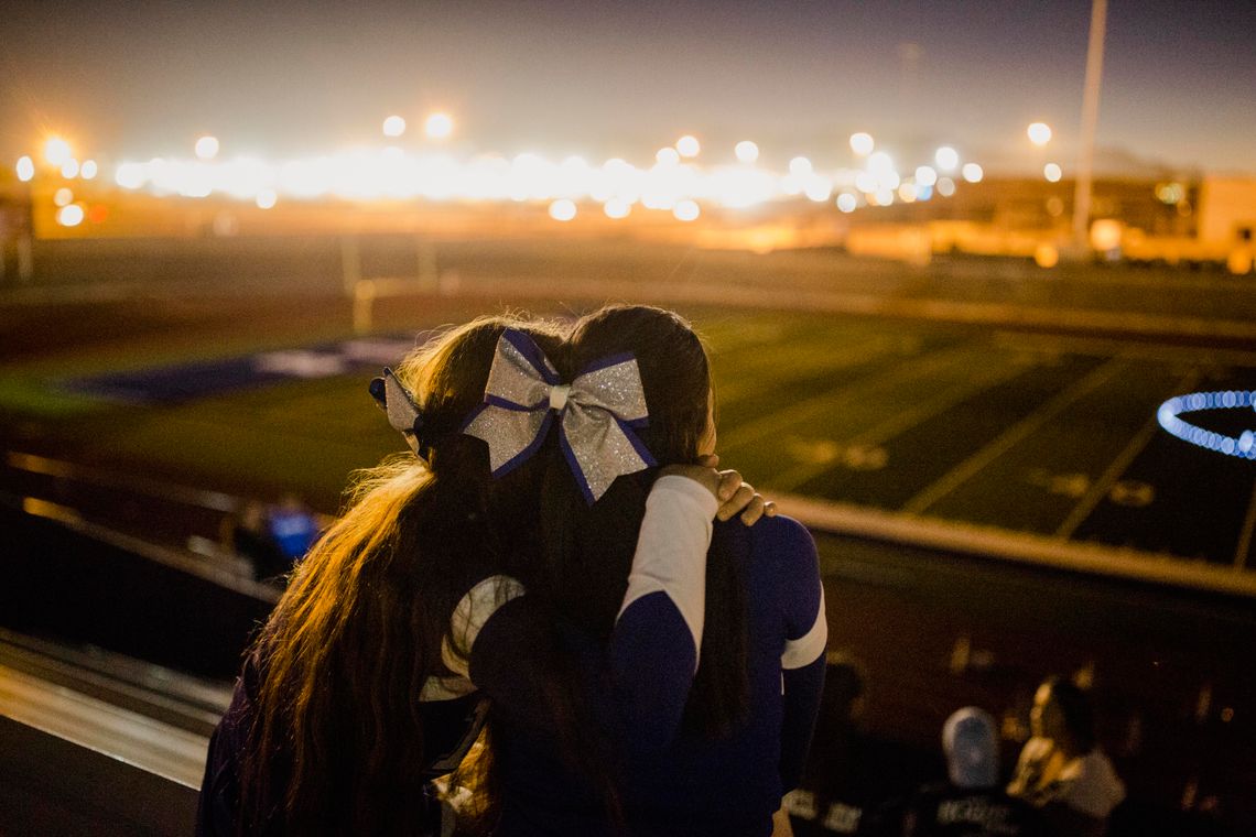 Cheerleaders Laysha Diego and Maleny Barba hold each other during the "Lighting of the B," a tradition to mark the end of football season. Maleny, who lives in Juárez, will often spend the night with Laysha in El Paso, so she doesn't have to cross the border late at night.