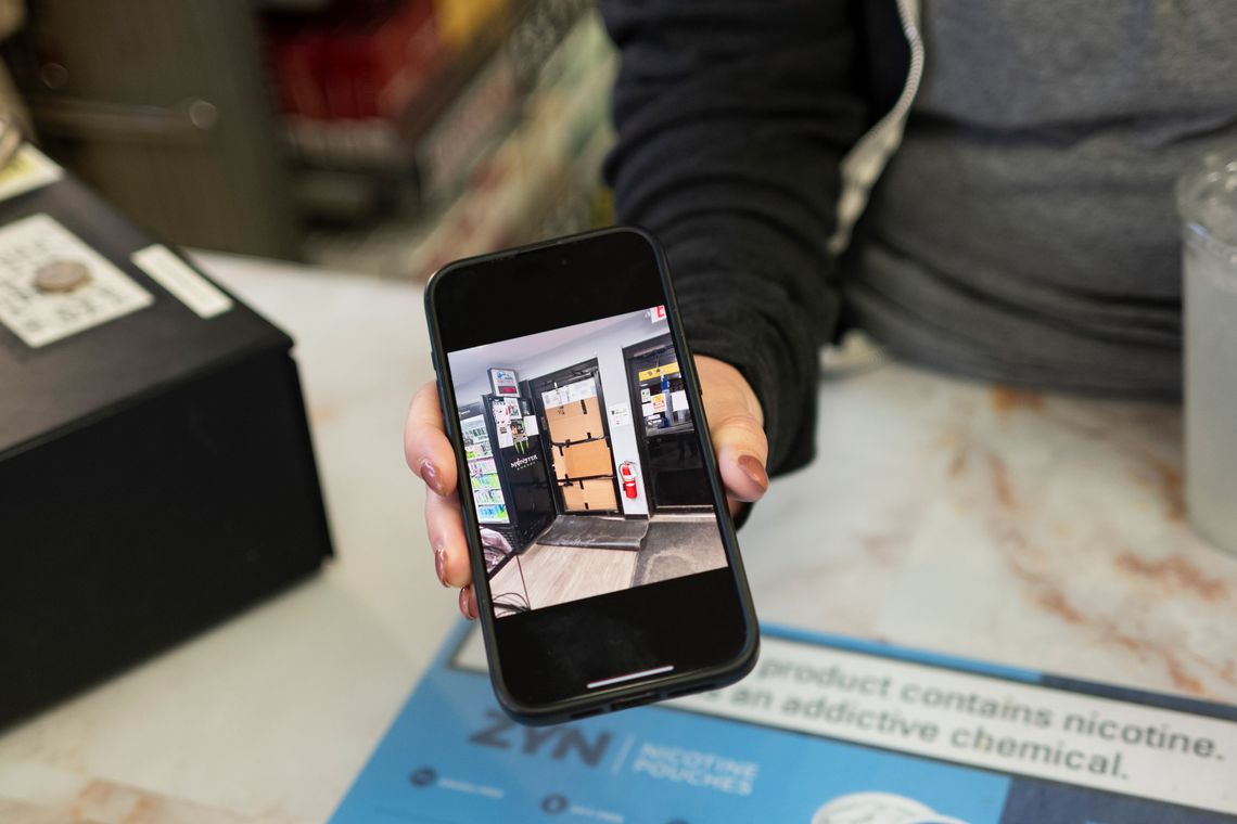 A woman’s hand holds her phone to show a photo of cardboard taped to a door.