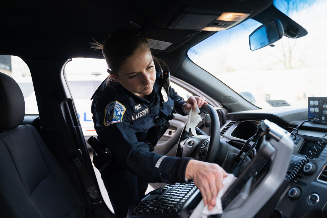 Officer Abby Kershek uses disinfectant wipes to sanitize her police cruiser after going off-duty on Monday. 