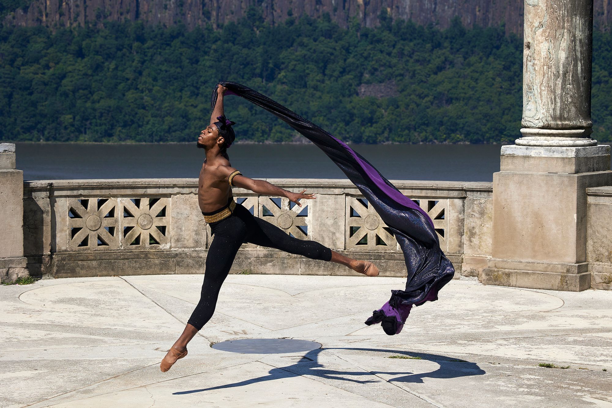 Khayr Muhammad leaps in the air with a cape in his right hand, streaming behind him.