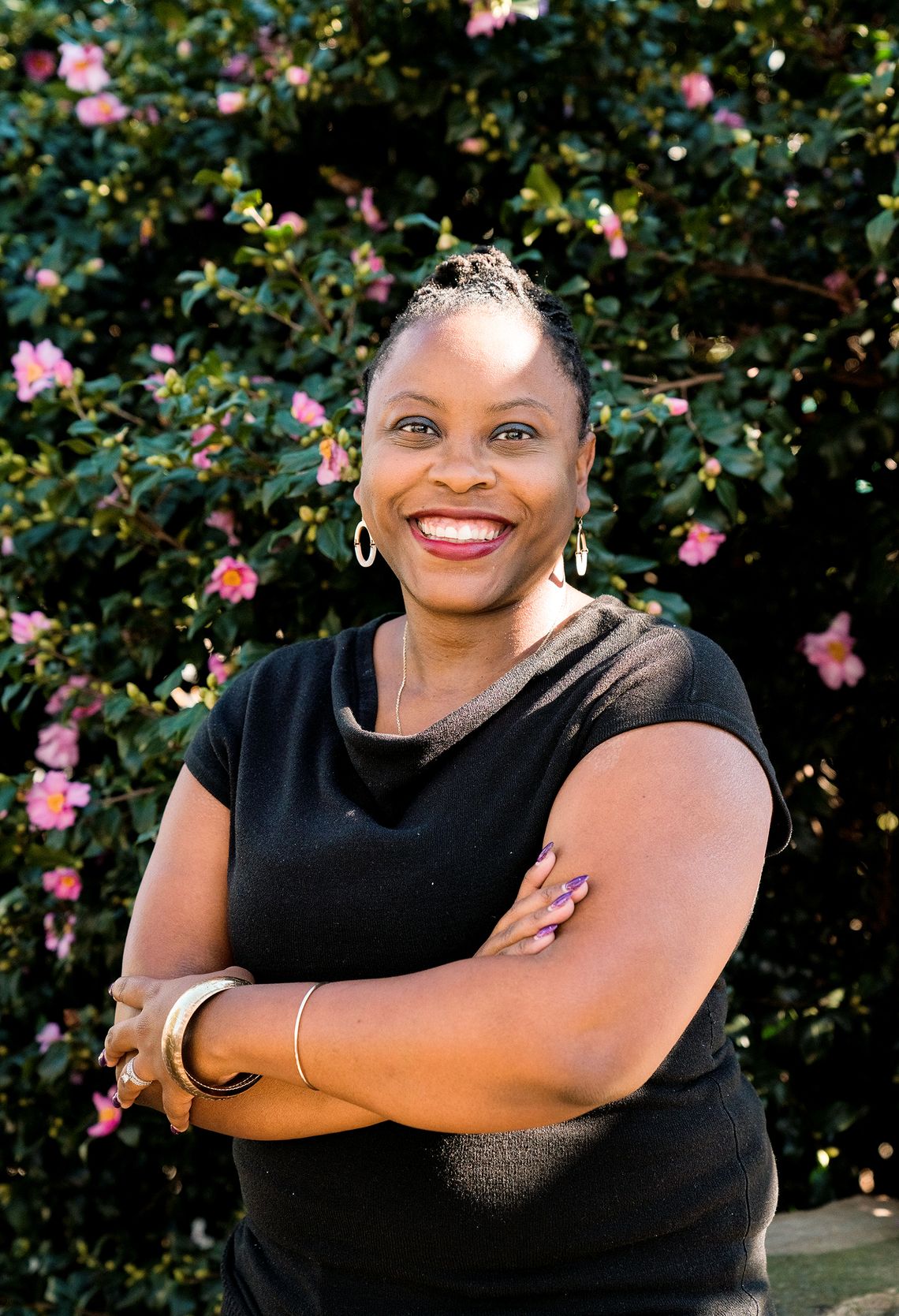 A woman with medium dark-toned skin wears a black shirt. 