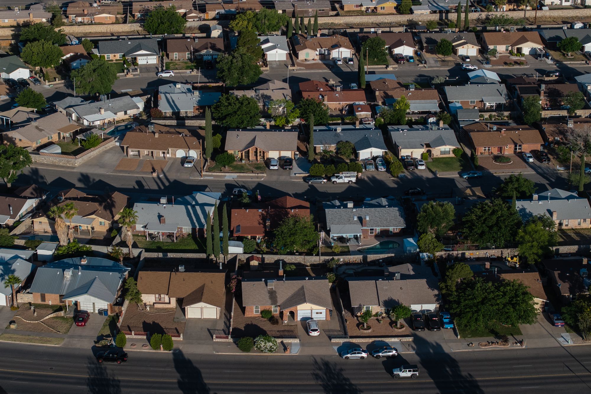 An aerial photo shows the suburbs of El Paso. More than two dozen houses are visible, along with trees. 