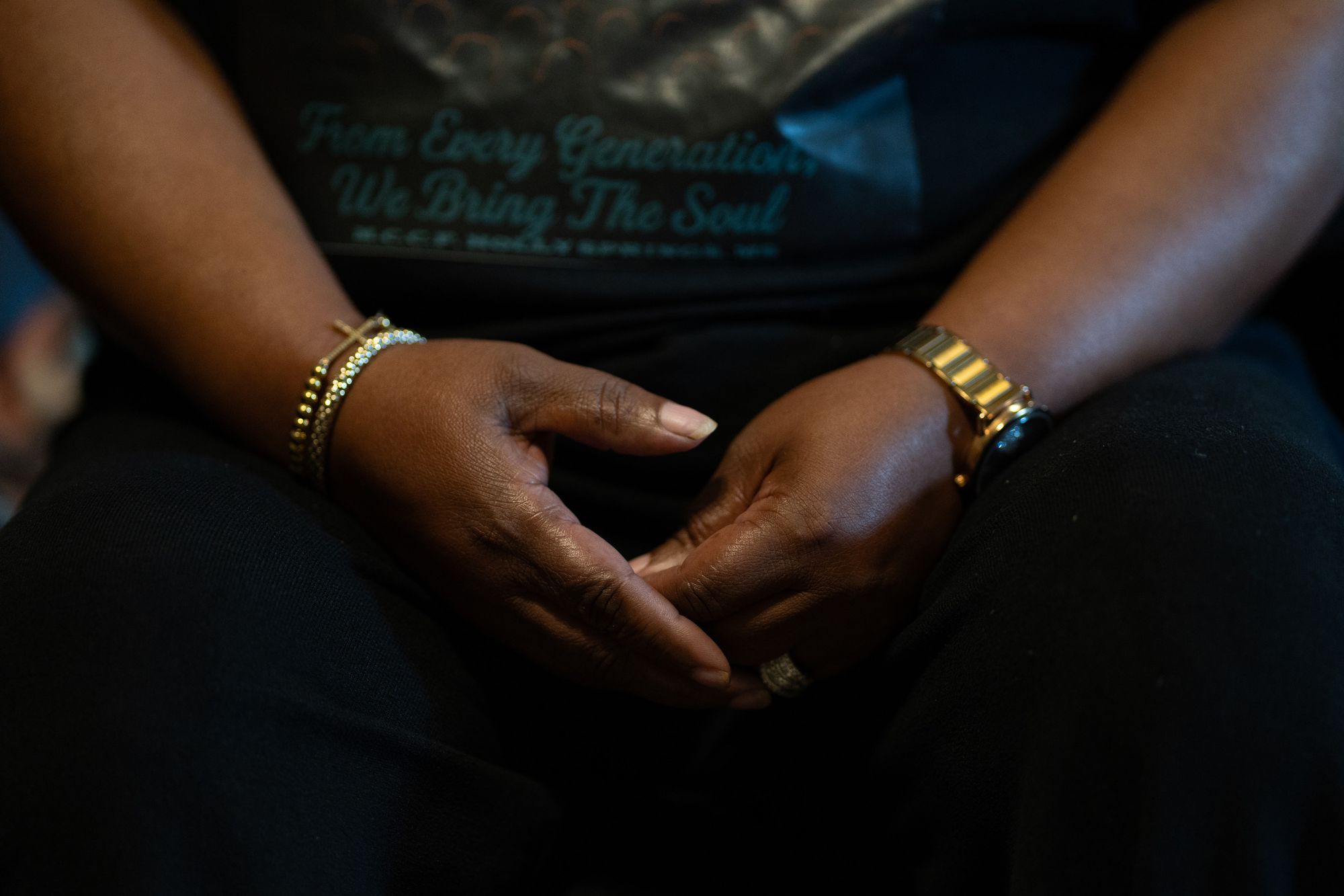 A close-up photo shows the hands of a Black woman wearing bracelets and a watch.