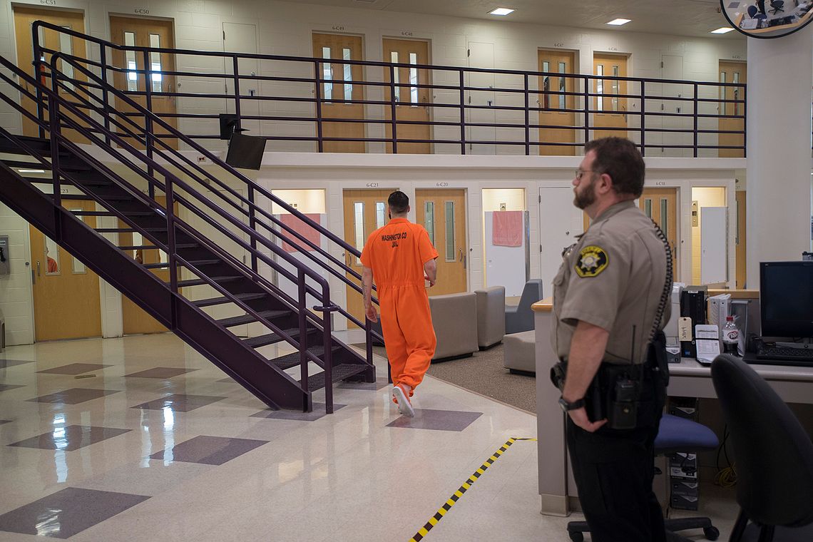 A prisoner walks to his cell at the Washington County Jail in Hillsboro, Ore., as a deputy looks on in 2018.