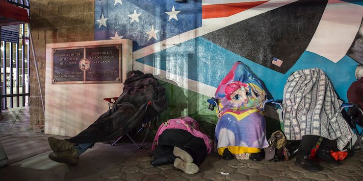 People slept wrapped in blankets in front of the Otay border crossing in Tijuana in May. The U.S. government decided to limit the opening hours of the border crossing to prevent the spread of the coronavirus, and many commuters sleep for hours on the Mexican side of the border to get to work on time in the morning.