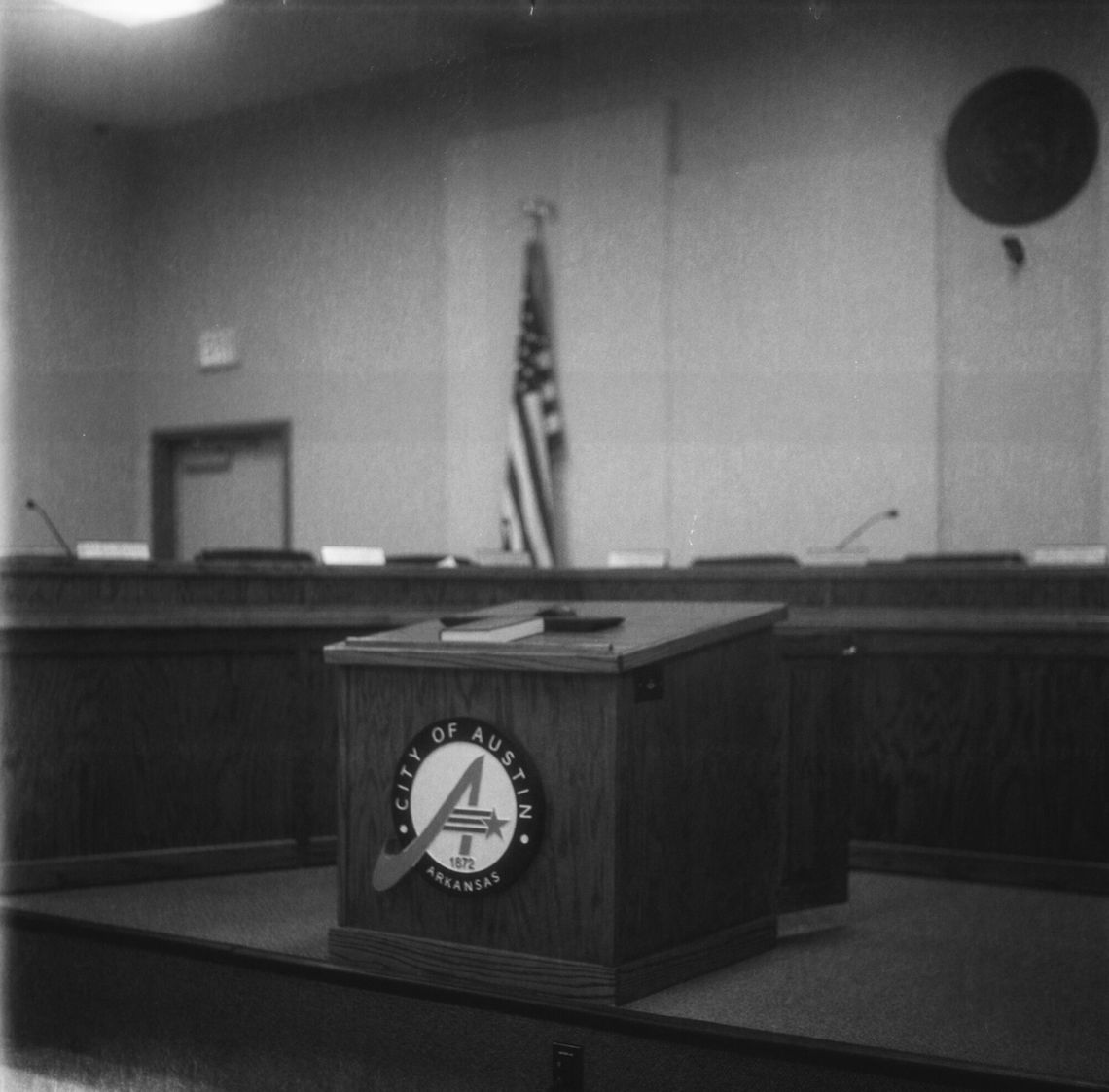 A black-and-white photo of a wooden table in a city council building. 
