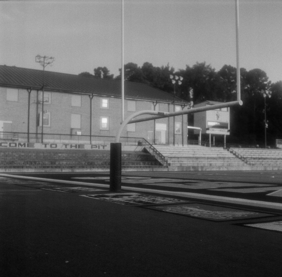 Three black-and-white photos show different views of a padded goalpost on a football field. 