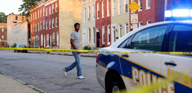 A man walks past a corner where a victim of a shooting was discovered in Baltimore in 2015.