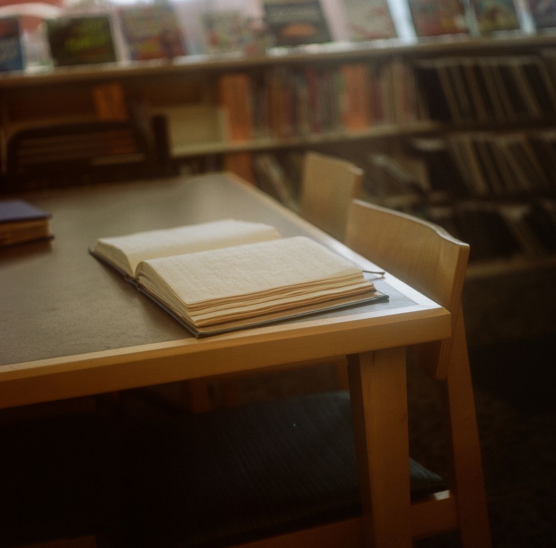 A color photo of a Braille book on top of a table at a library. 
