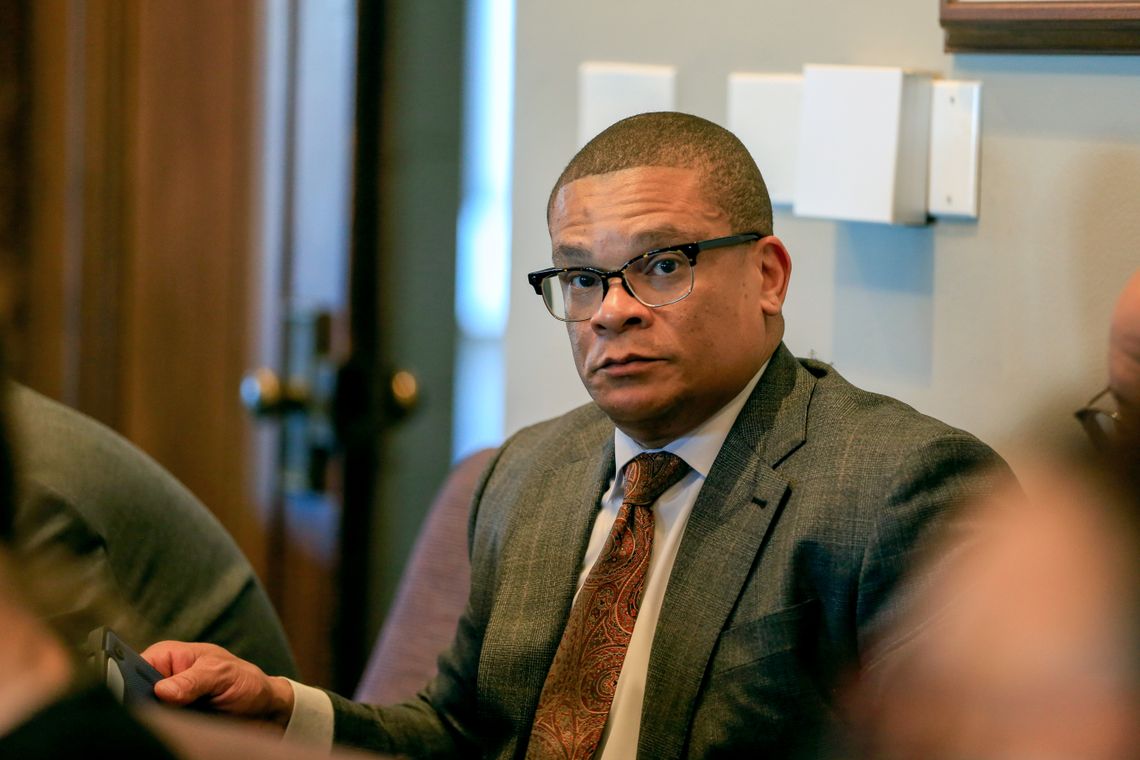 A photo of Karrie Howard, a Black man in a gray suit and wearing glasses. 