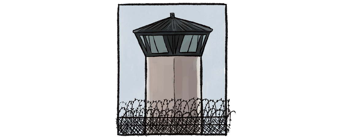 A watch tower rises above the top of a fence with razor wire.