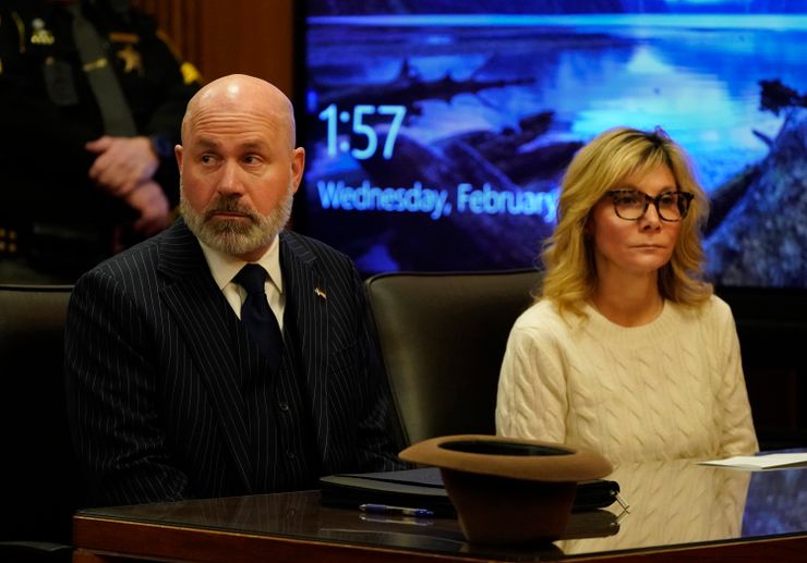A photo shows Leslie Ann Celebrezze, right, a White woman with blonde hair and glasses, wearing an ivory sweater, sitting next to her attorney, Ian Friedman, a White man with a gray beard and wearing a black suit, in a courtroom.