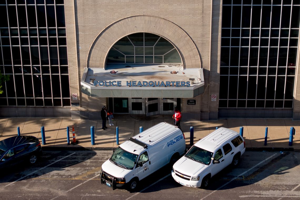 A view from above the awning of the police department headquarters’ entrance. Three vehicles are parked in front of the doors. 