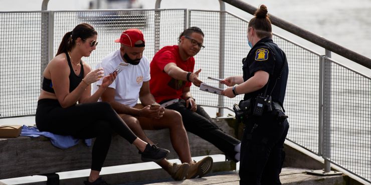 Yonkers Police Officer Ashley Callery hands out cards with information about social distancing to people at the park at Getty Square, Yonkers, in May.   