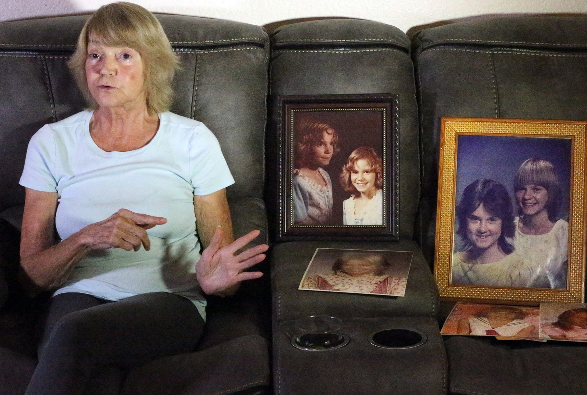 Fulton, a White woman with blonde hair, sits on a gray couch next to picture frames holding photos that show her daughter Desiree, a young White girl. 