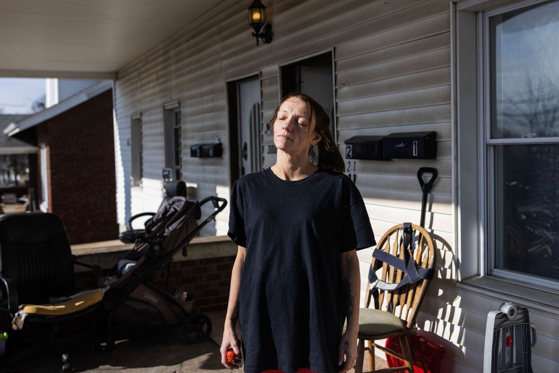 A photo of a White woman on a porch with her eyes closed while facing the sun.