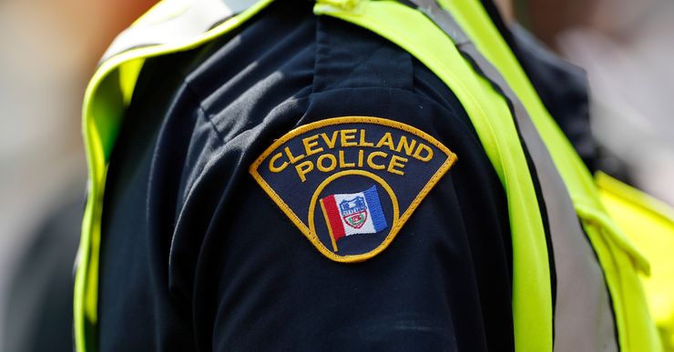 An officer in a neon green vest with a shoulder badge that reads "Cleveland Police." 