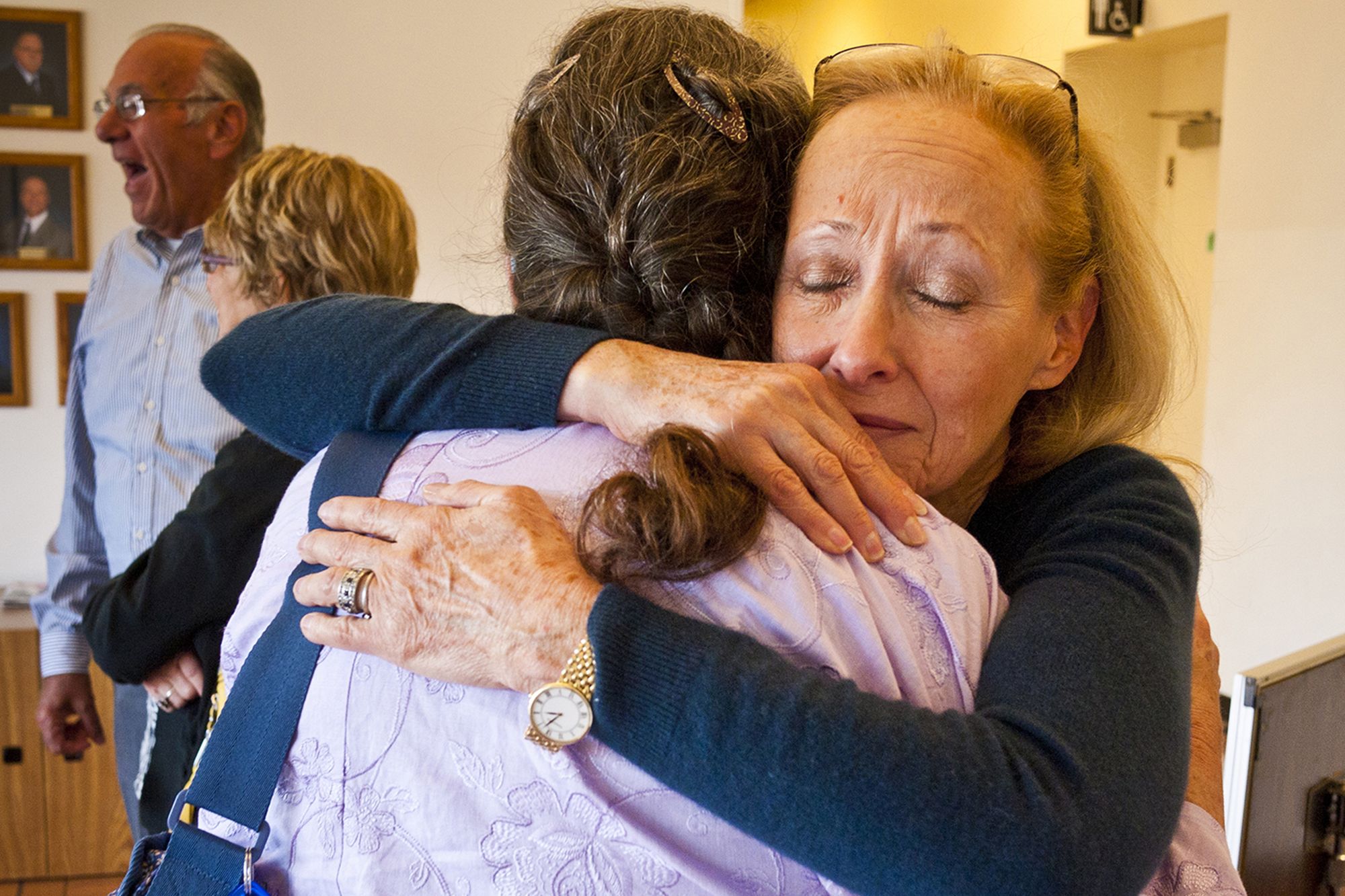 Louise Kane, a White woman with blonde hair, hugs a woman with dark brown hair. 