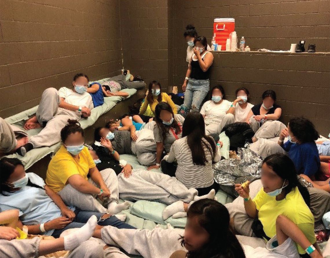 A group of women is sitting very close to each other in a concrete cell. 