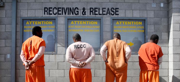 Men await processing after arriving at the Deuel Vocational Institution, a state prison in Tracy, Calif. 