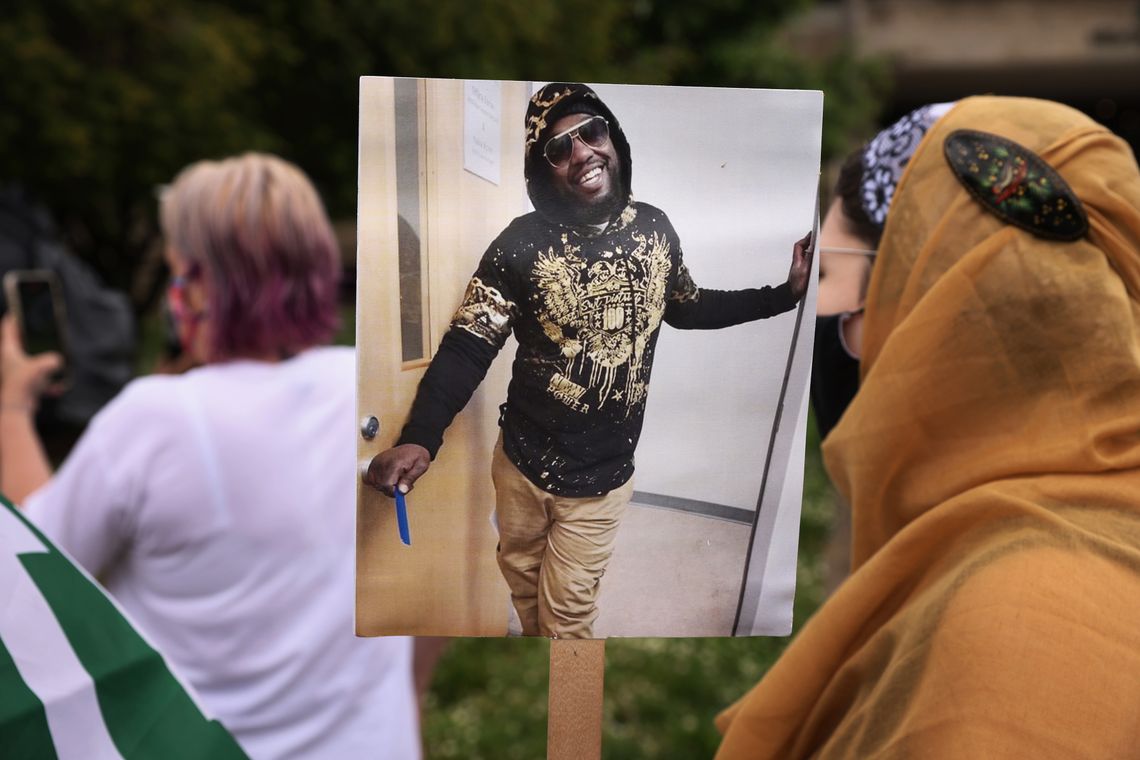 A protester at a May 3, 2021 demonstration holds a picture of Marcus Smith, who died after police hogtied him on a Greensboro, N.C. street in September 2018.