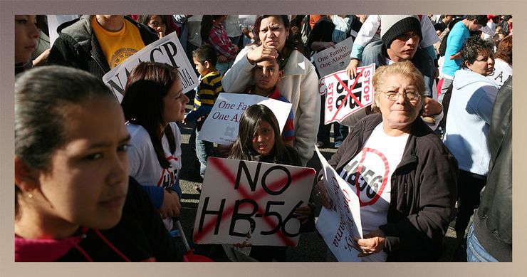 A photo shows a crowd of mostly Latino people of different ages holding signs and wearing shirts against HB-56. 