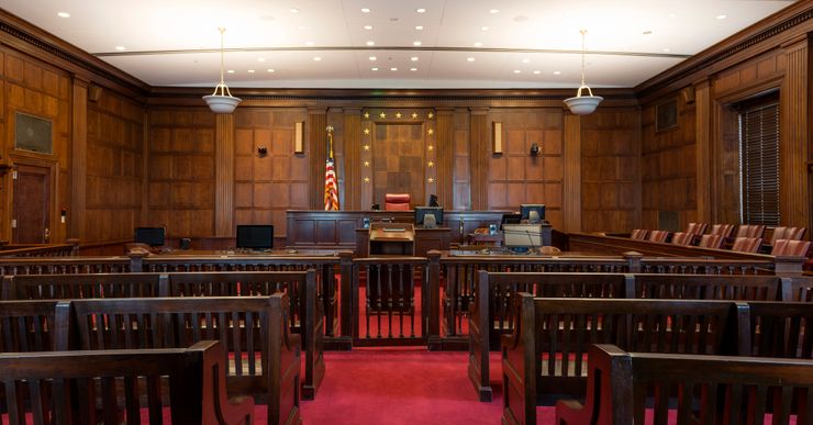 The wood-paneled and red-carpeted inside of an empty courtroom. 