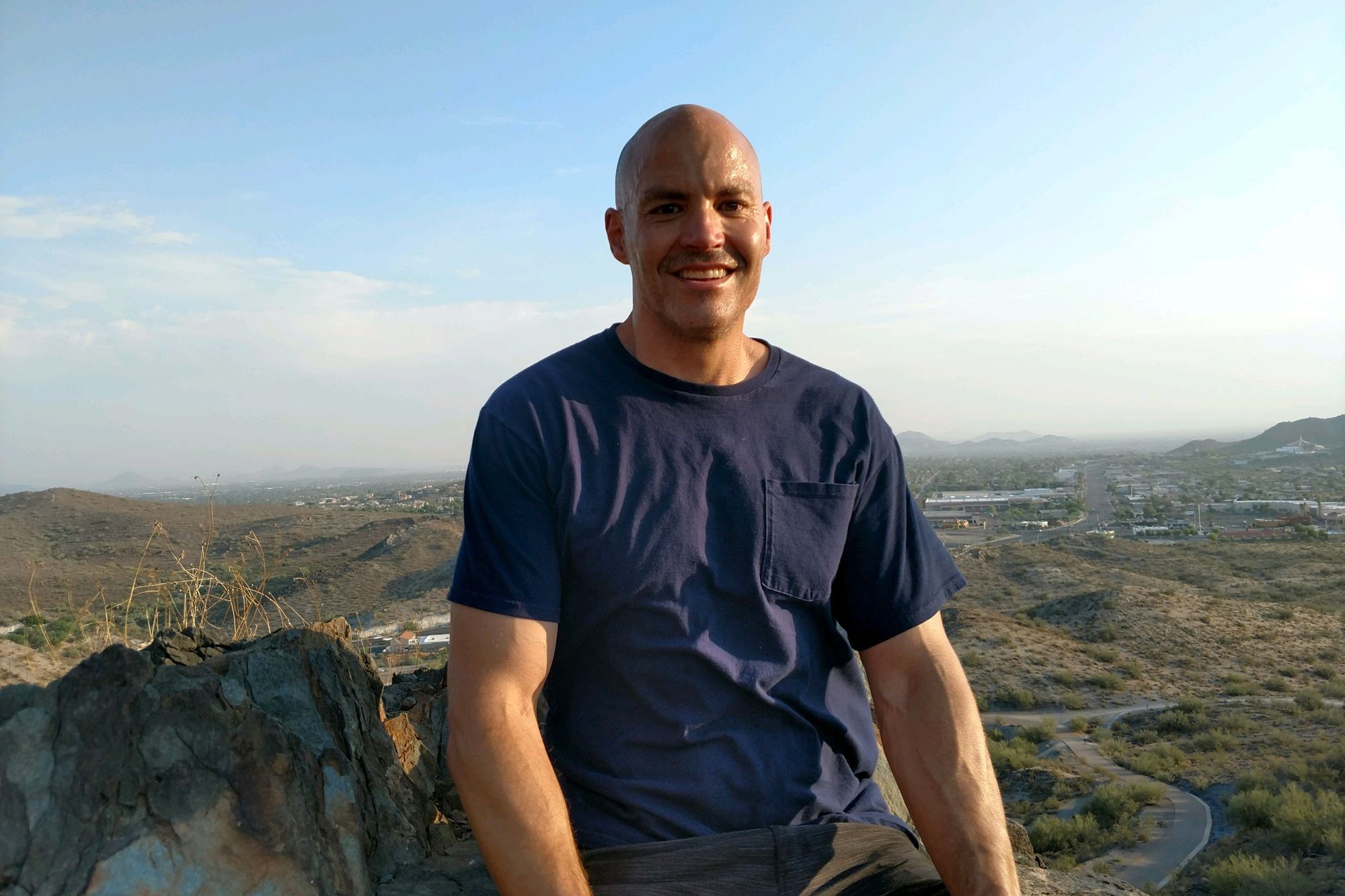 Jacob Wideman, a multiracial man, poses in front of a valley. A road winds into the distance. 