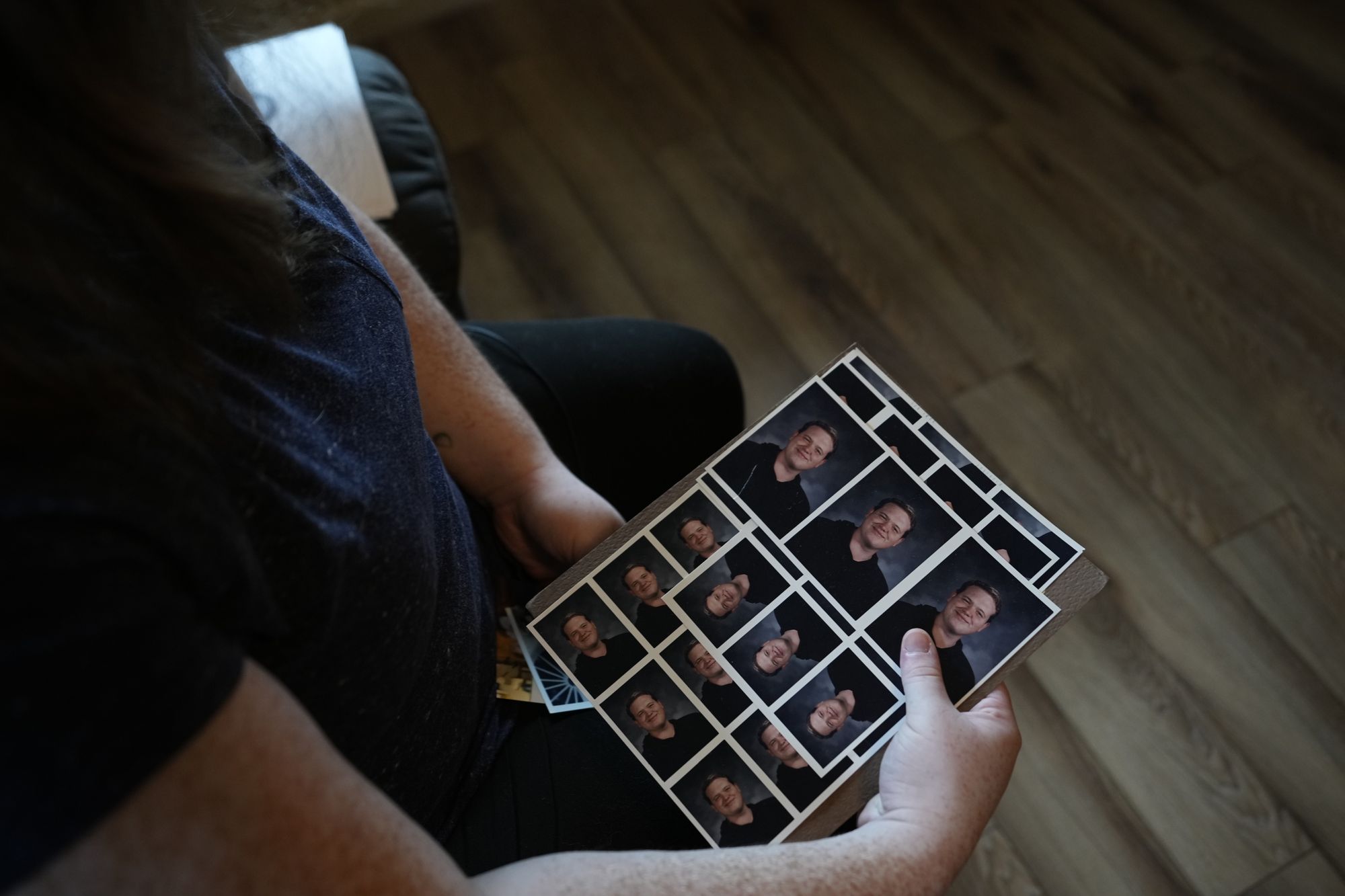A photo shows Katherine Dixon, a White woman, holding photos of her father, Aaron Dixon. Her face is not visible. 