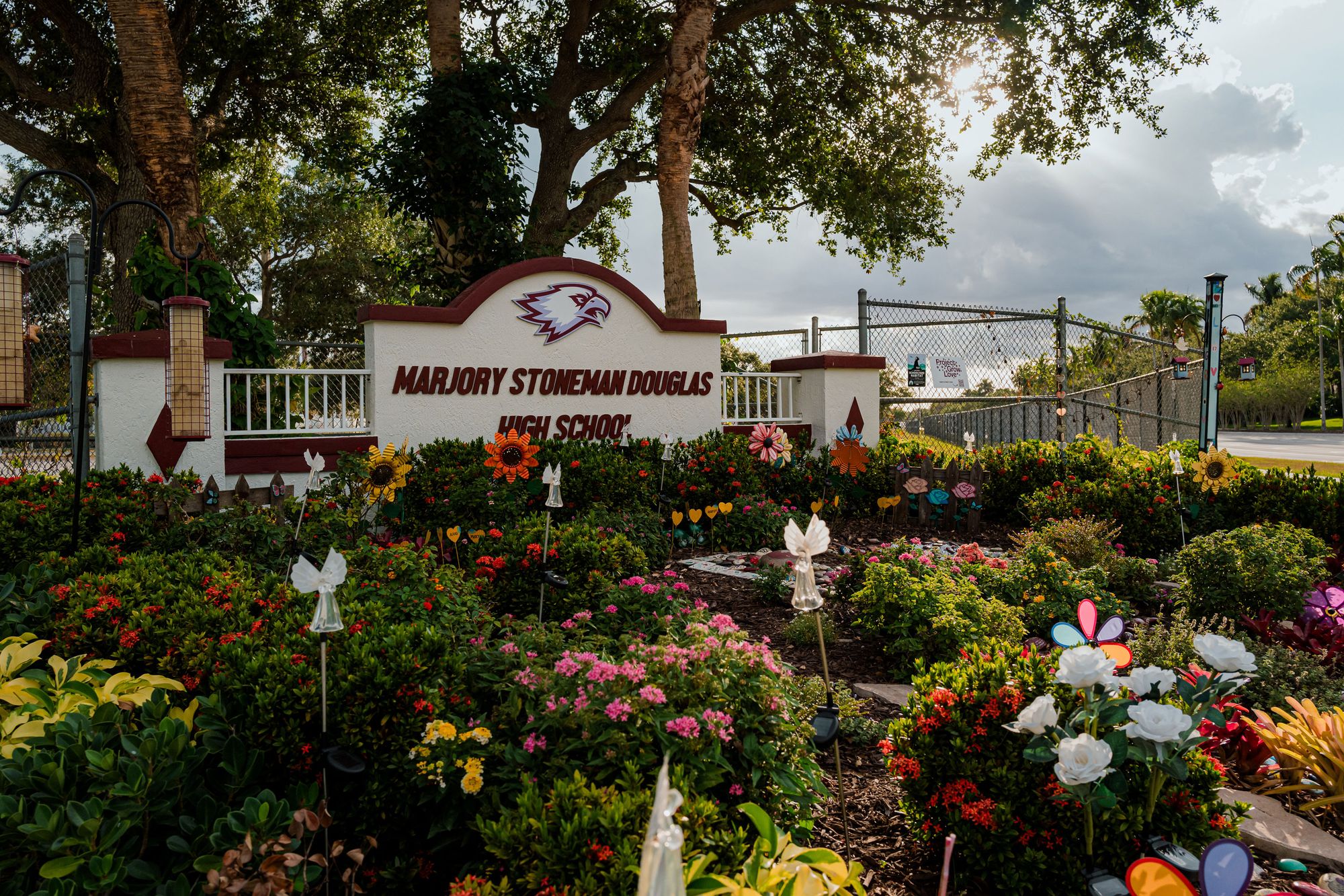 A photo of a garden with flowers and angel-shaped garden stakes next to a sign that reads “Marjory Stoneman Douglas High School.” 