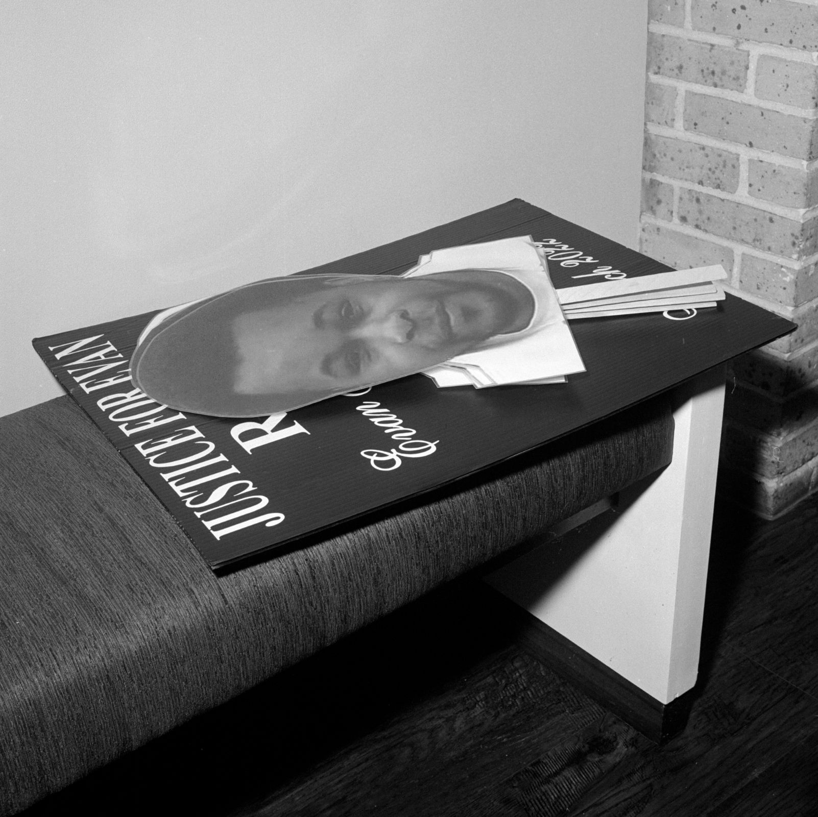 On a bench, a sign with a cutout of Evan’s face rests on a sign that reads “Justice for Evan.