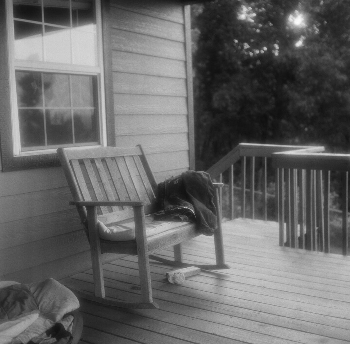 A black-and-white photo of a Carhartt work jacket draped over a bench on a porch. 