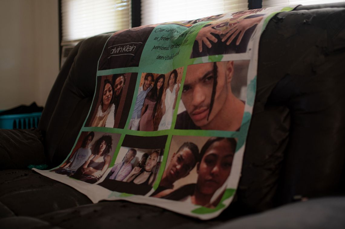 A photo of a green blanket with family photos and text is draped over the back of a couch. 