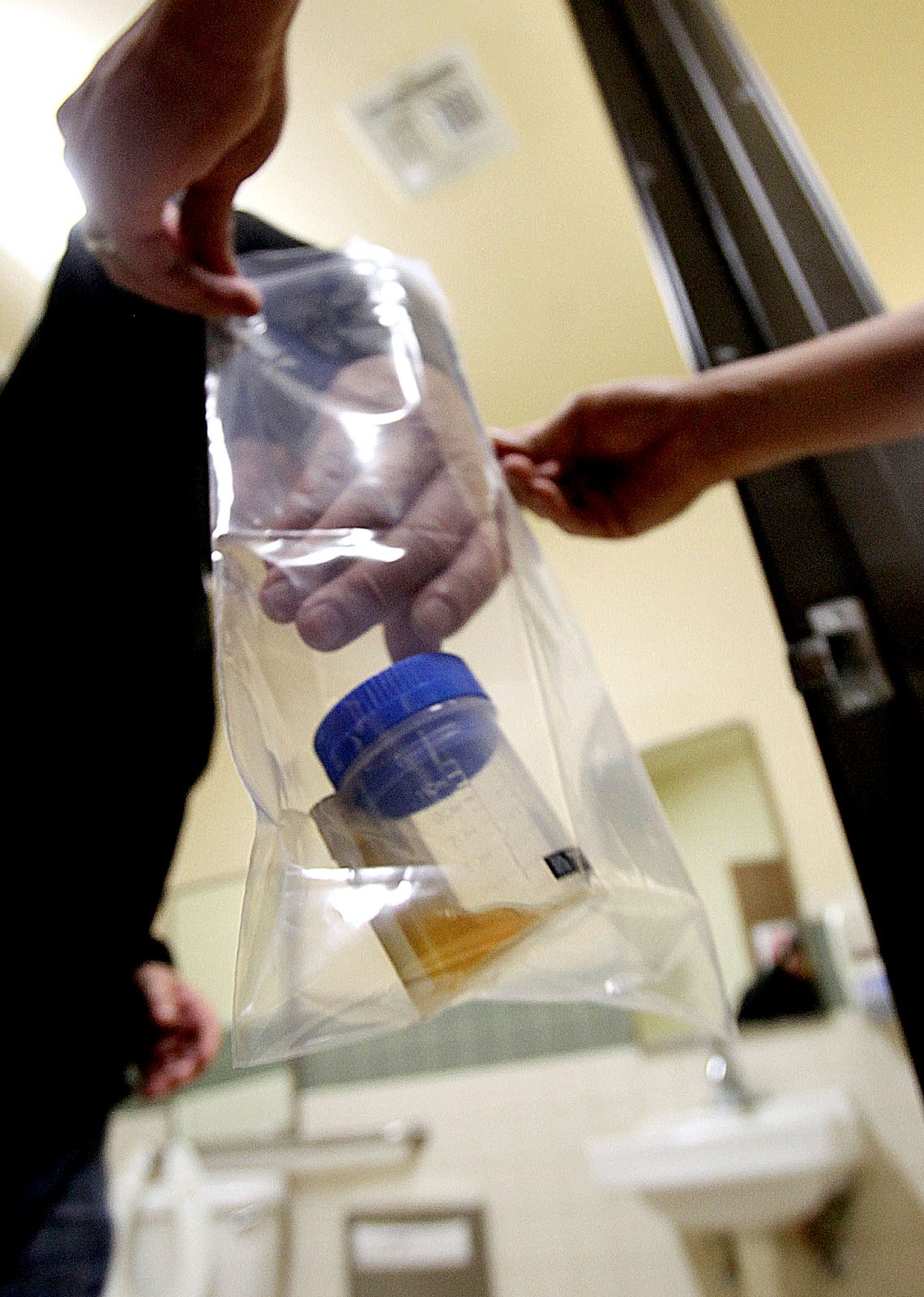 In this photo taken May 19, 2011, parolee Larry Winters, places a urine sample he has just given for drug testing, to William Chao, a parole services associate, at the parole office Sacramento, Calif., Thursday, May 19, 2011. Winters, 65, is among a group of parolees participating in the Project HOPE program that California prison officials hope will reduce the rate of parolees returning to prison. Under Project HOPE, parolees must subject themselves to frequent supervised drug testing. If drugs are detected, they will be locked up in county jail for a few days instead of returning to prison for about four months. (AP Photo/Rich Pedroncelli)