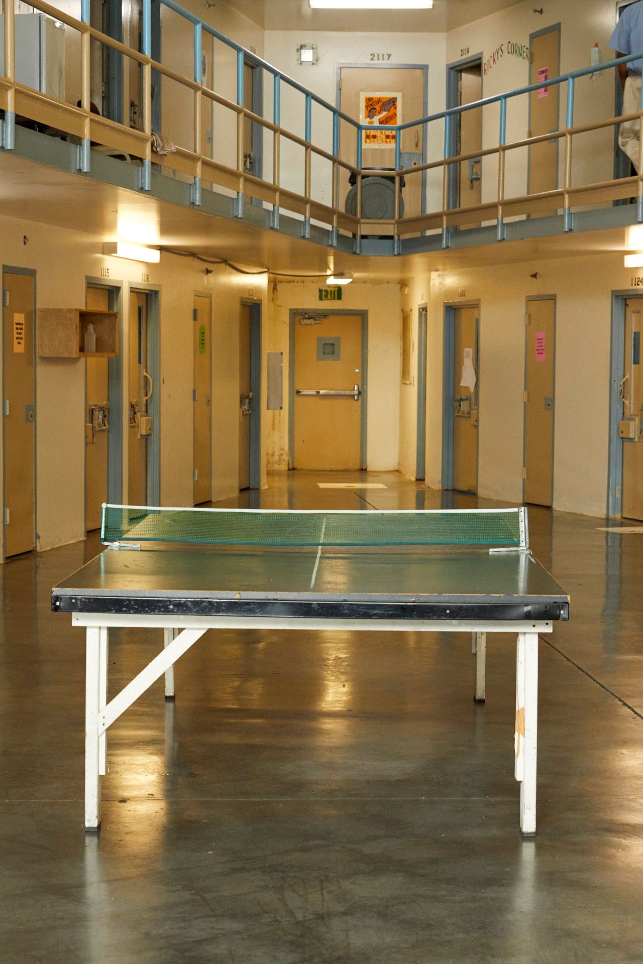 A ping-pong table sits in the middle of a room surrounded by doorways on the ground floor of the Lee Correctional Institution. A second-floor balcony is ringed with another set of doors, including one with the words “Ricky’s Corner” painted next to it.