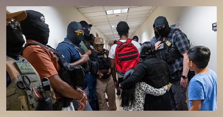 Masked federal agents, including members of ICE, stand on either side of a hallway. A person wearing a white T-shirt and red backpack walks down the center of the hallway with their back to the camera. A woman and a young child, both with dark hair, walk behind the person with their arms around each other. A young boy with dark hair and a blue T-shirt follows behind them. 