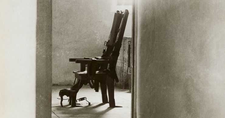 A black and white photo of an empty electric chair through a doorway. 